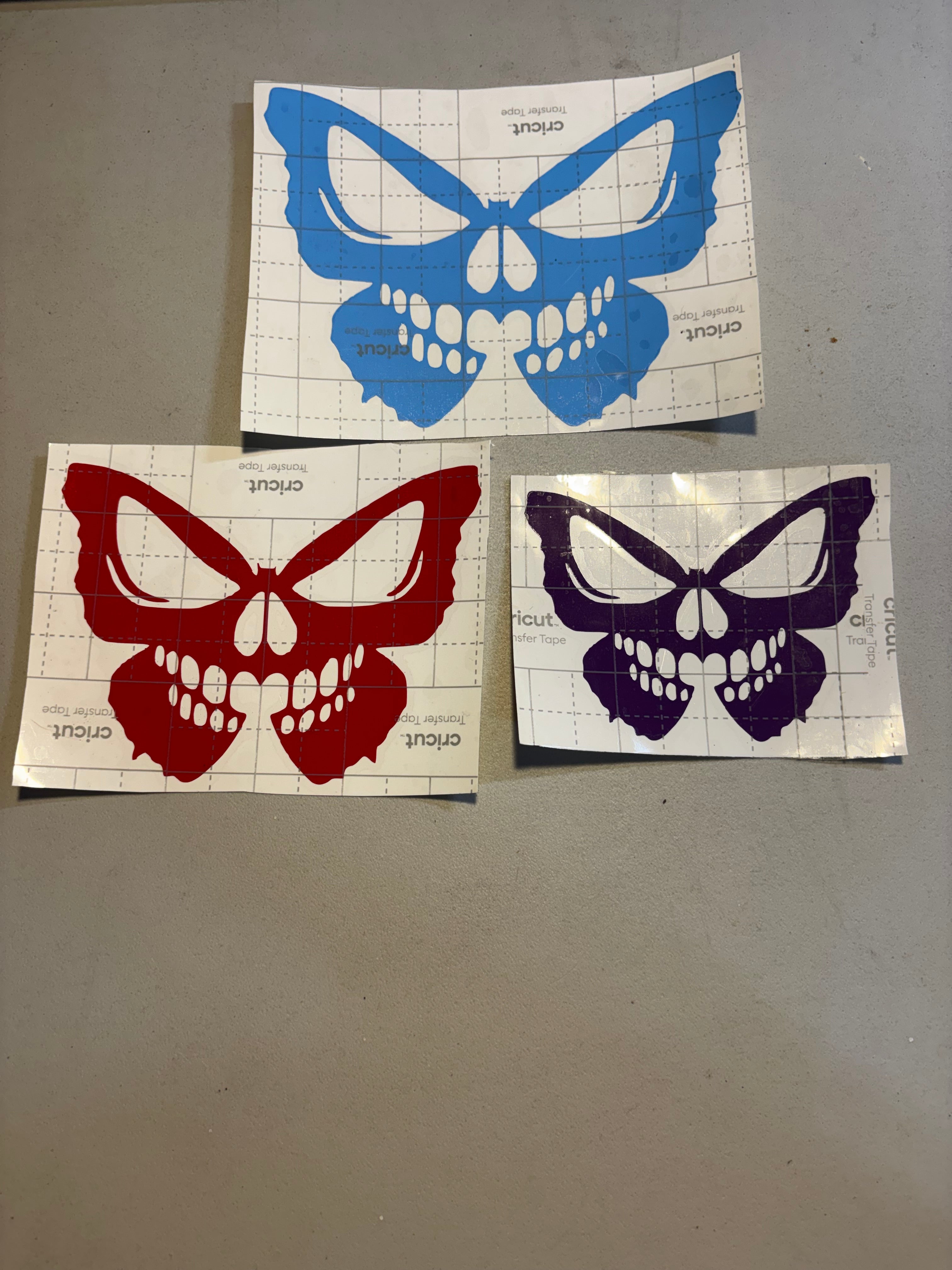 Butterfly skull design shown in blue, red, and purple